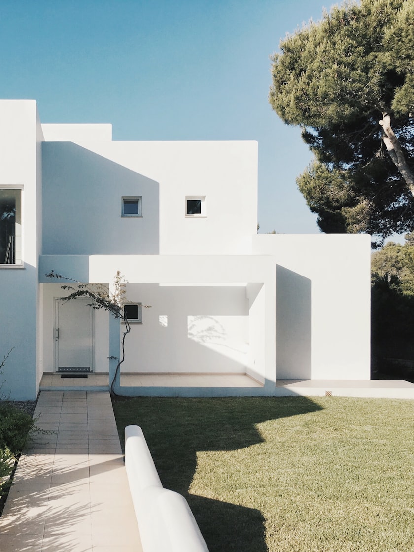 A white rendered house of stacked cubic volumes against a clear sky.