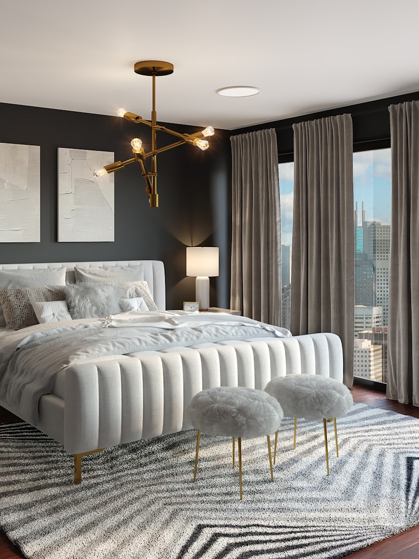 A bedroom with a channelled upholstered bed, dark walls and a brass light.