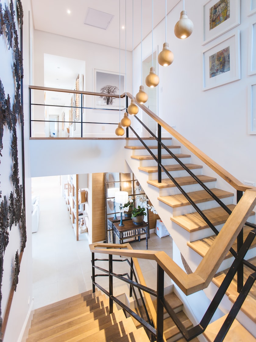 An open timber and steel staircase rising through a bright double-height hall.