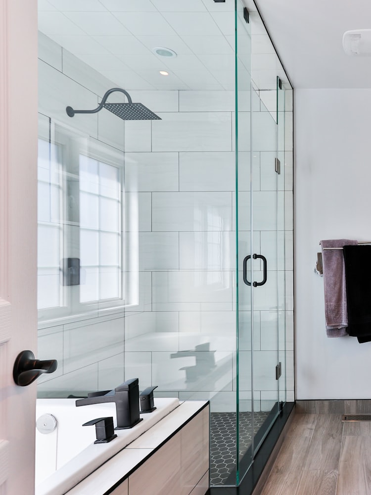 A bathroom with a glazed shower, a floating vanity and matt black fittings.